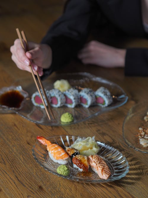 Hands Holding Chopsticks over Sushi