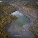 航拍风景展现了宁静的采石场湖，它被郁郁葱葱的森林悬崖环绕，尽显大自然的美丽