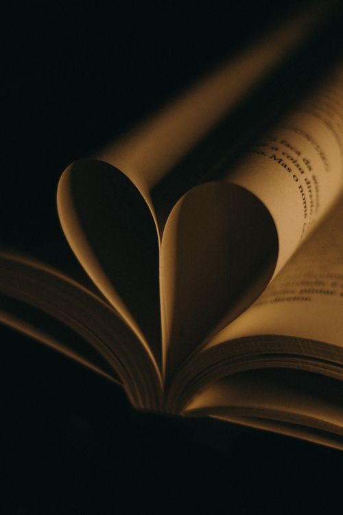 Free A warm and artistic still life of book pages folded to form a heart shape, perfect for literature lovers. Stock Photo