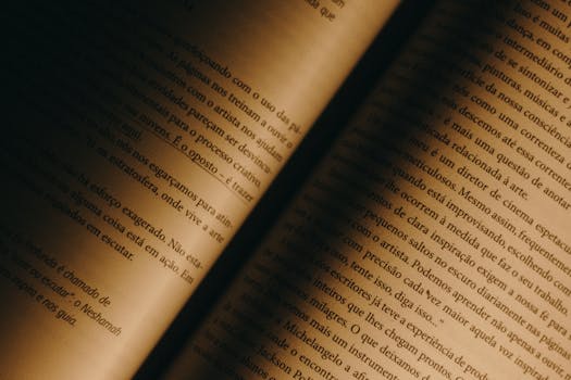Close-up of old book pages with warm lighting, showcasing yellowed paper and Portuguese text.