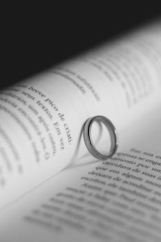 A romantic scene with a ring casting a heart shadow on book pages.
