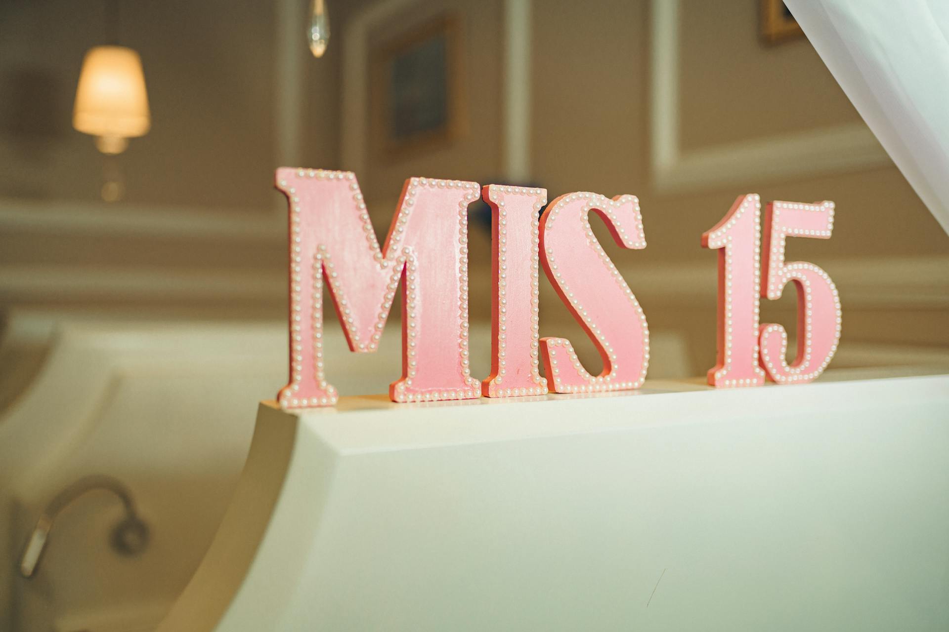 Elegant MIS 15 sign in pink with delicate pearls, perfect for quinceañera decor.