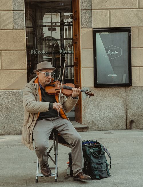 Free A street musician plays the violin on a Milan sidewalk, adding charm to the urban atmosphere. Stock Photo