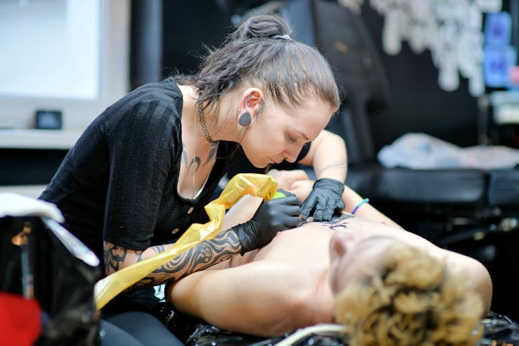 Woman Making Tattoo To Man