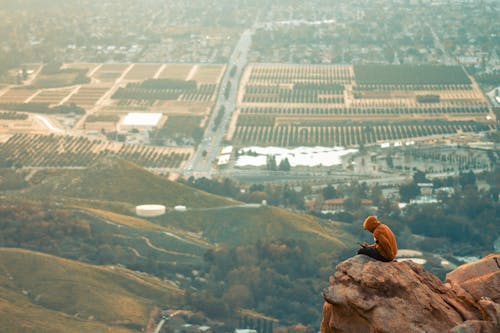 Aerial View of a Man Sitting on the Edge of a Mountain 