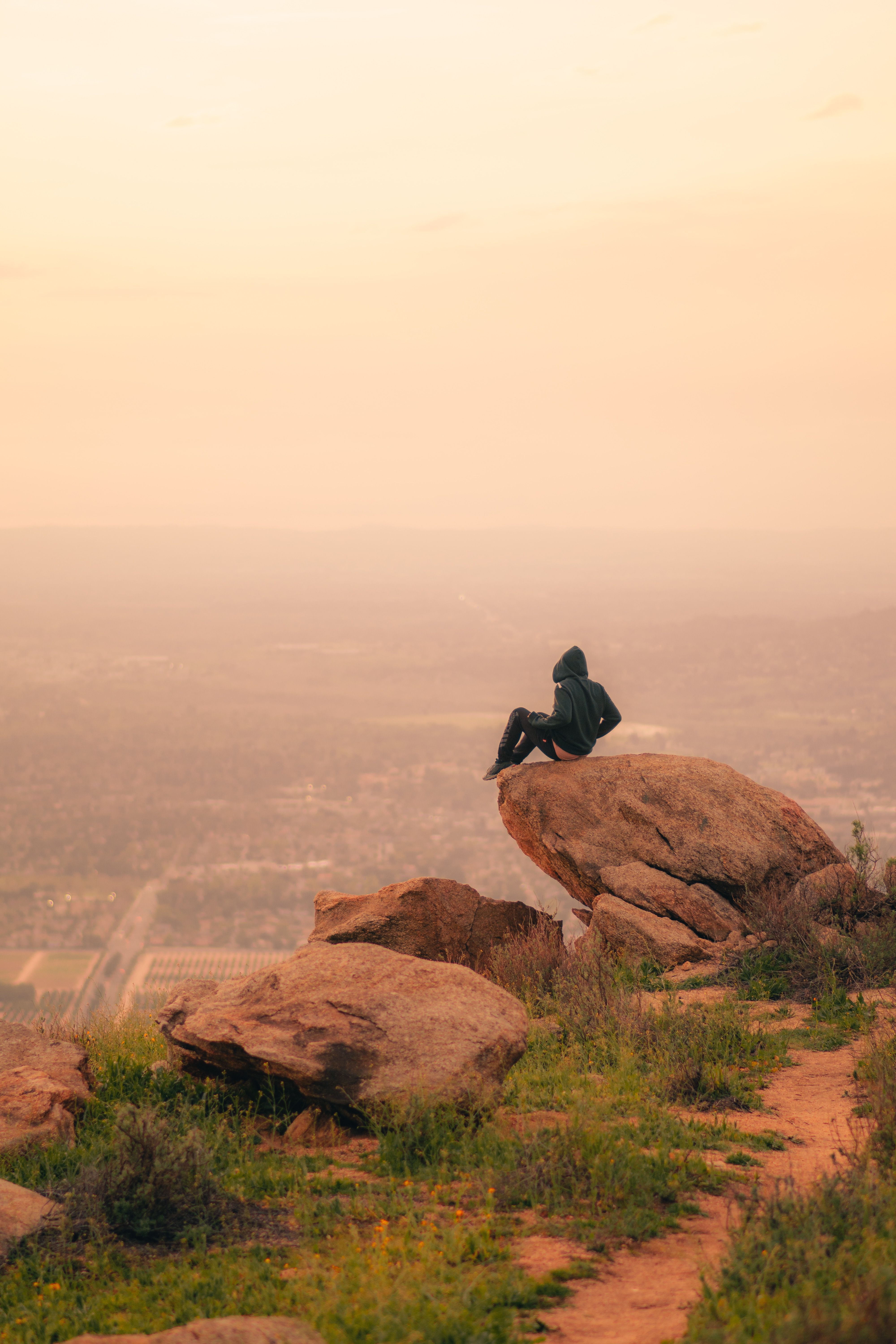 Person Sitting on Rocks over Plains at Dusk · Free Stock Photo