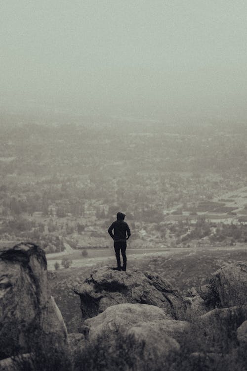 Back View of a Person Standing at the Edge of a Rock