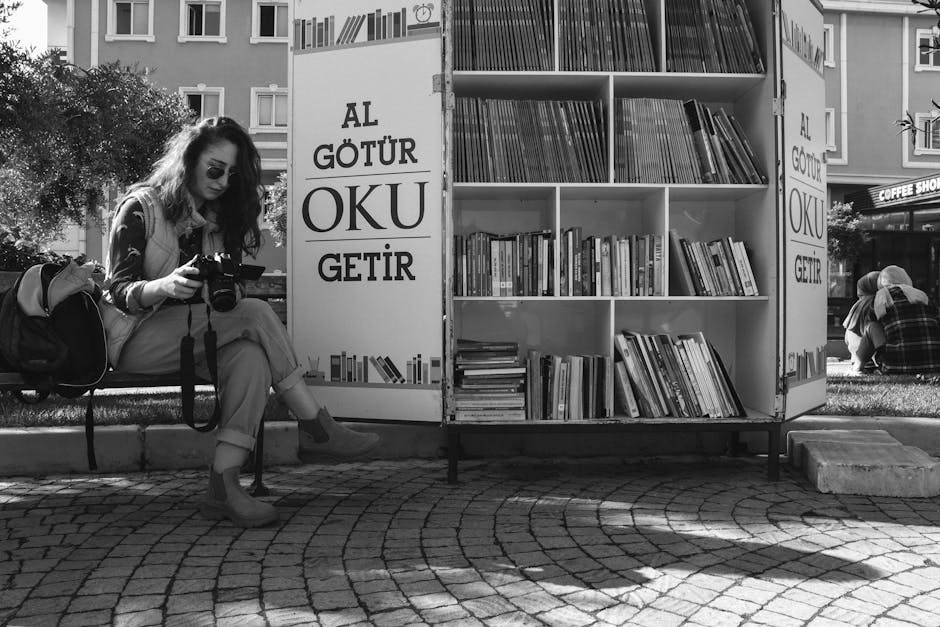 A woman photographing an outdoor bookshelf on a sunny day in an urban area, capturing the essence of street literature.