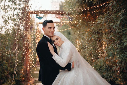 Happy Bride and Groom Hugging in Garden with Lights