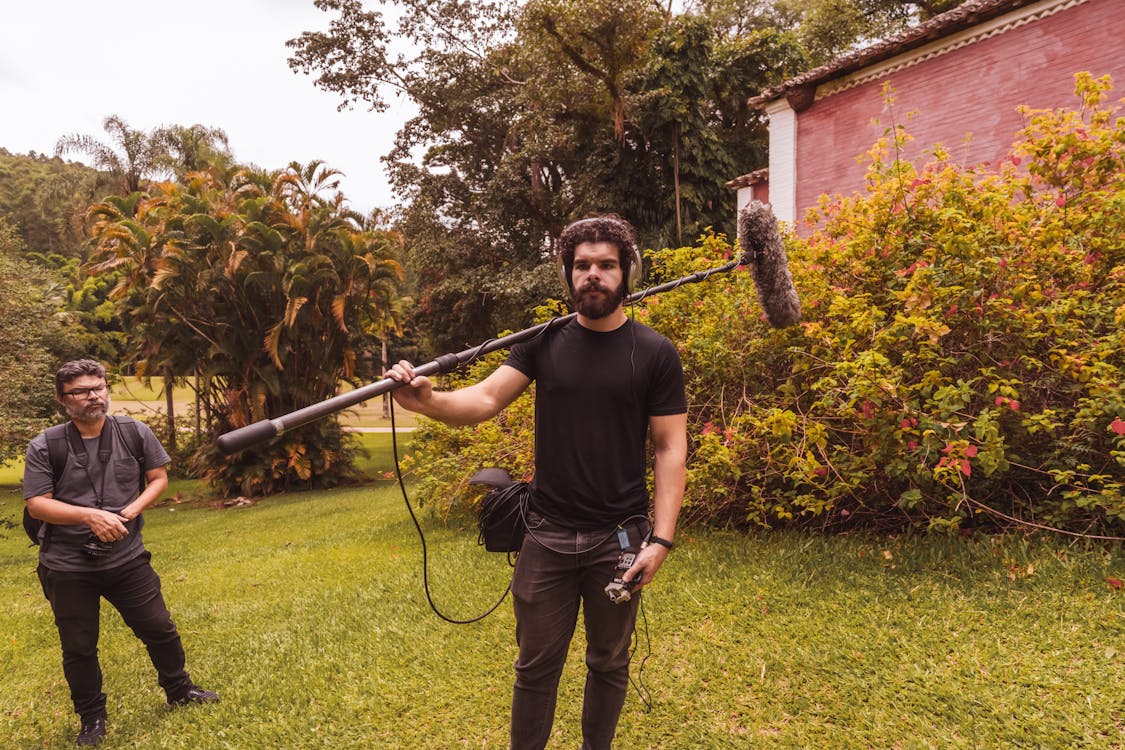 A man holding a boom mic on the set of a film.