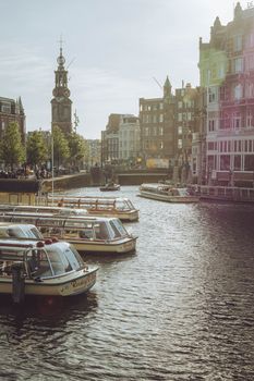Scenic Amsterdam canal with moored boats and historic architecture on a sunny day.