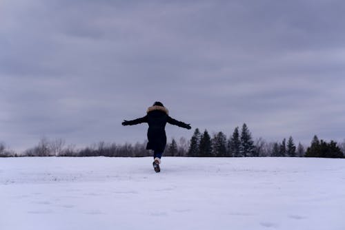 Woman in Winter Clothing Running on a Winter Field 