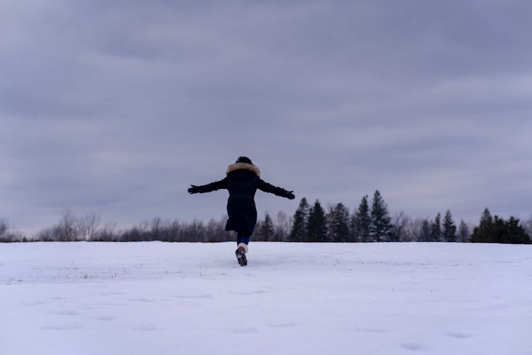 Woman In Winter Clothing Running On A Winter Field 