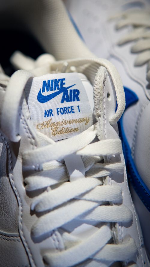 Free White Nike sneakers featuring blue accents and anniversary edition label. Stock Photo