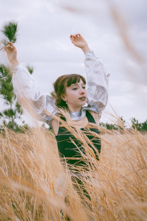 Photo of a Cute Young Woman Dancing in a Wheat Field