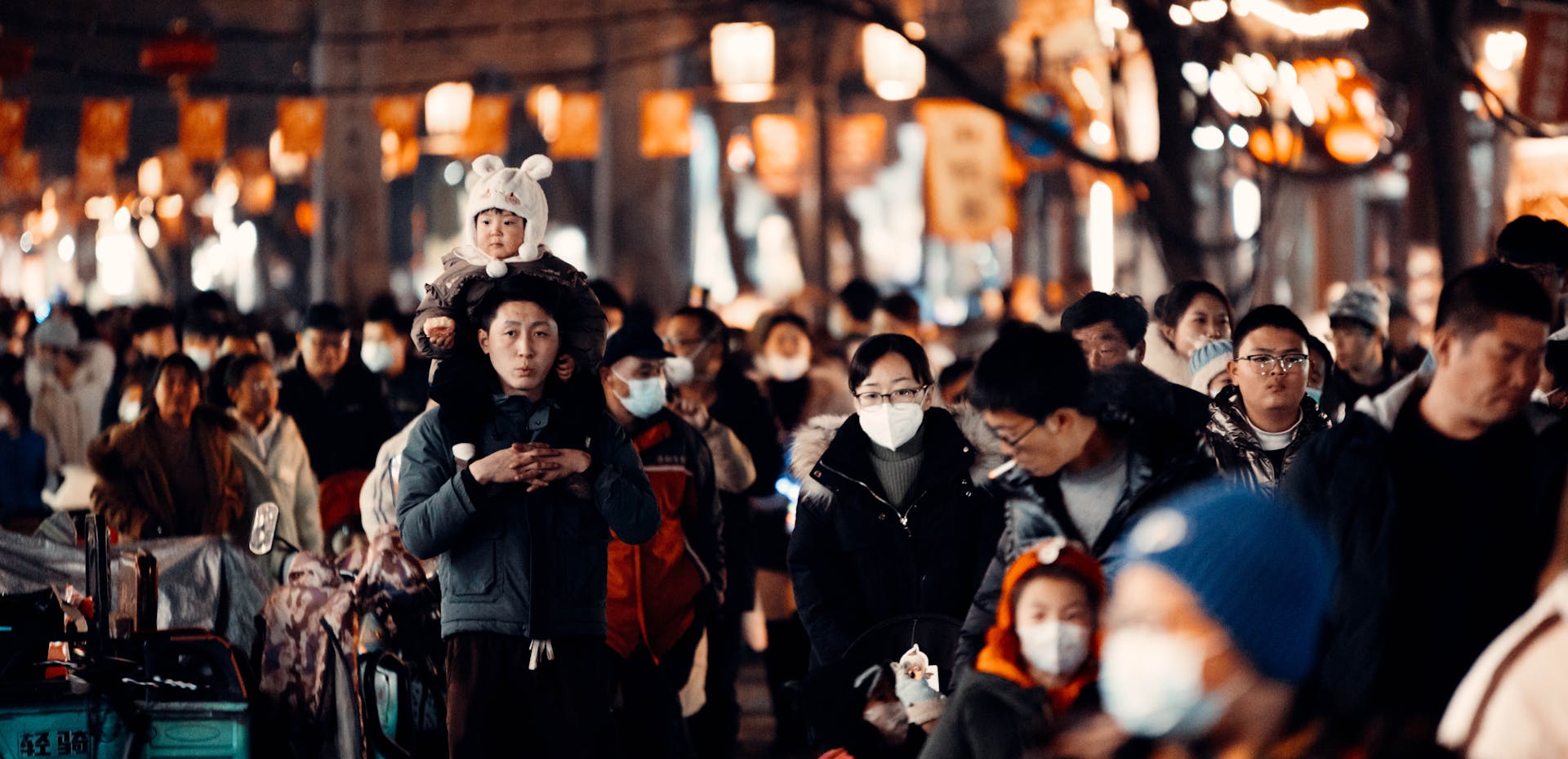 Mask-wearing crowd on a festival street in Weifang, China, capturing the bustling atmosphere.