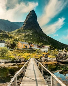 Explore the picturesque landscape of Vågan, Nordland with a stunning wooden bridge leading to colorful houses.
