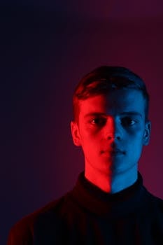工作室环境中，男性肖像半亮，点缀着艺术性的红蓝灯光