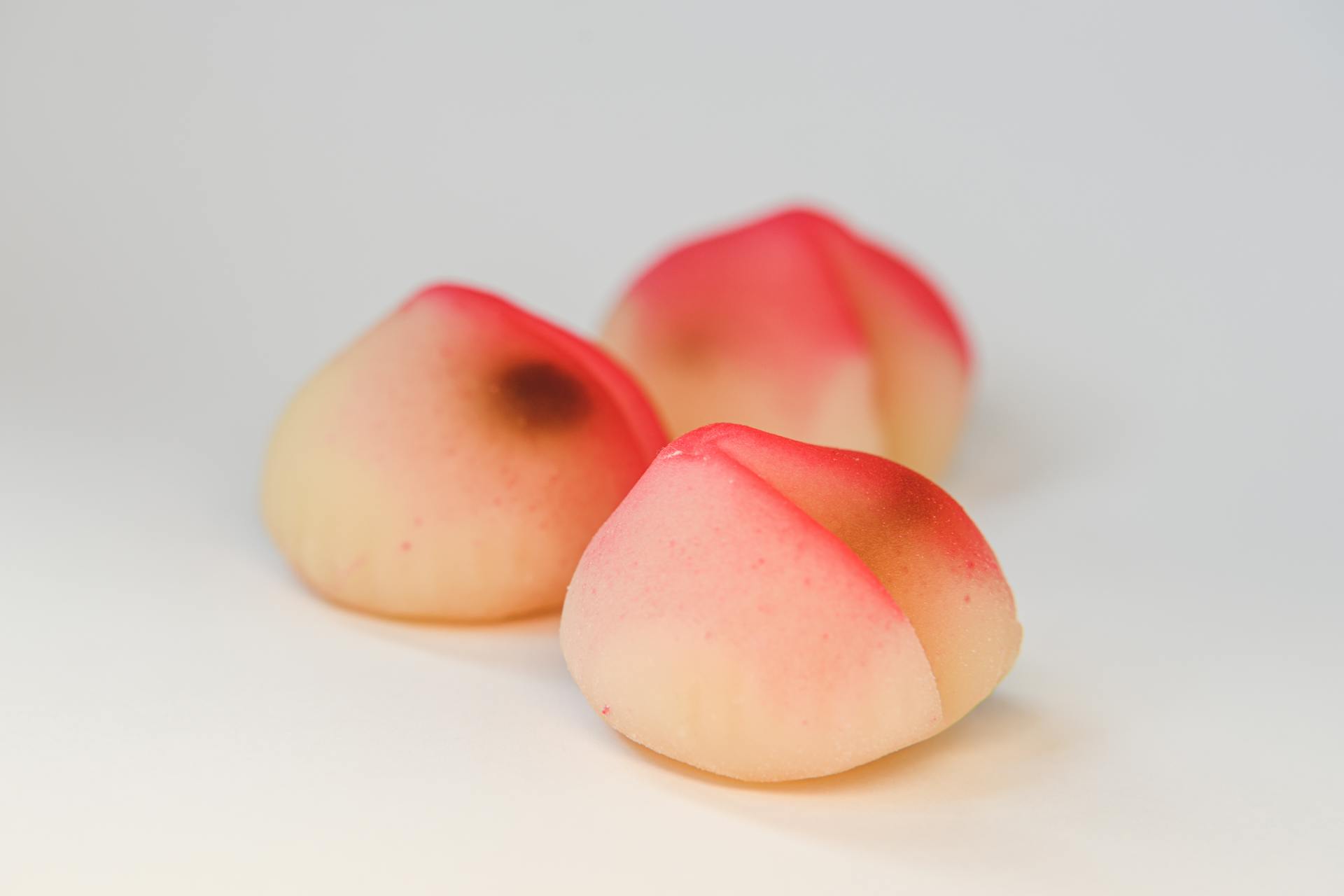 Close-up of three colorful longevity peach buns, symbolizing good fortune and health.