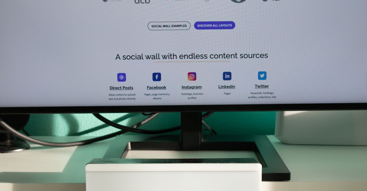 A clean and modern desk setup with a lightbox displaying '#TREND' and a computer monitor showing a social wall solution.
