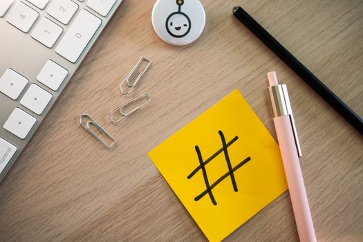 Top view of a modern desk with a hashtag sticky note, keyboard, and stationery items.