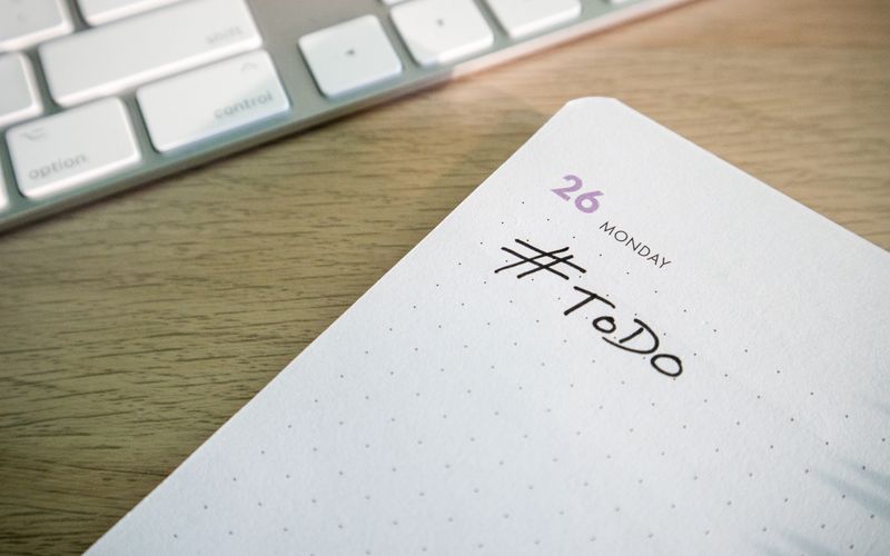 Close-up of a to-do list next to a computer keyboard on a desk.