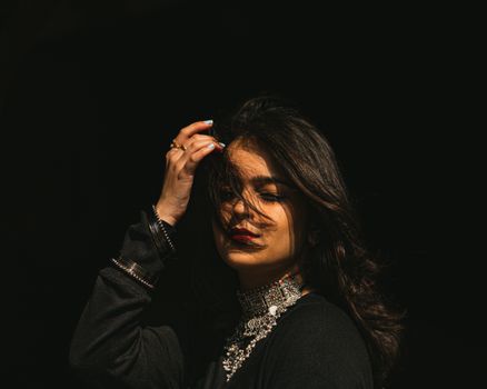 Striking portrait of a woman with jewelry against a dark background, capturing elegance and mystery.