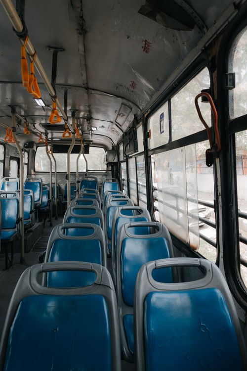 Free A detailed view inside a public bus with empty blue seats and hanging handles. Stock Photo
