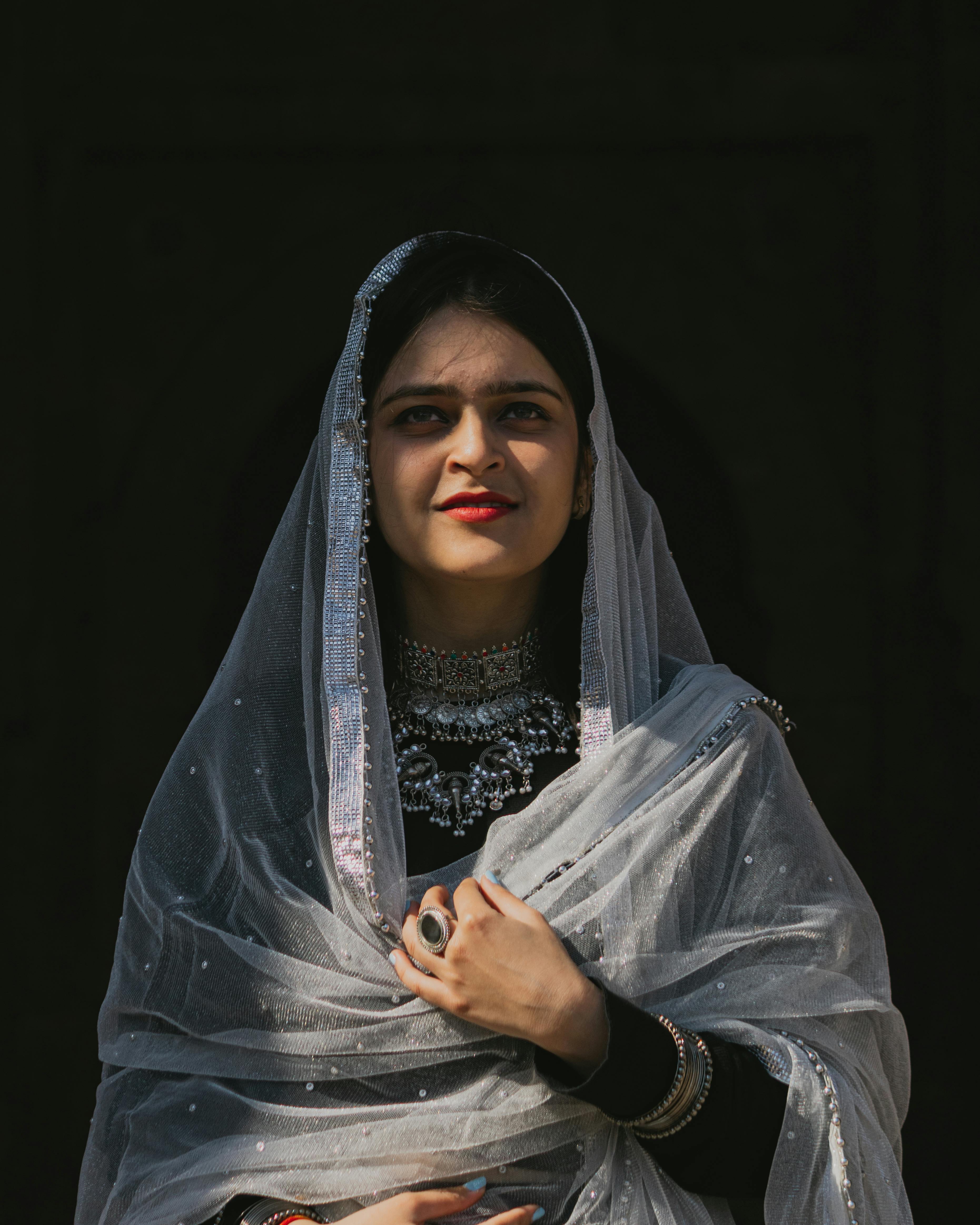 Portrait of a smiling young woman wearing traditional clothing with a veil in natural sunlight.