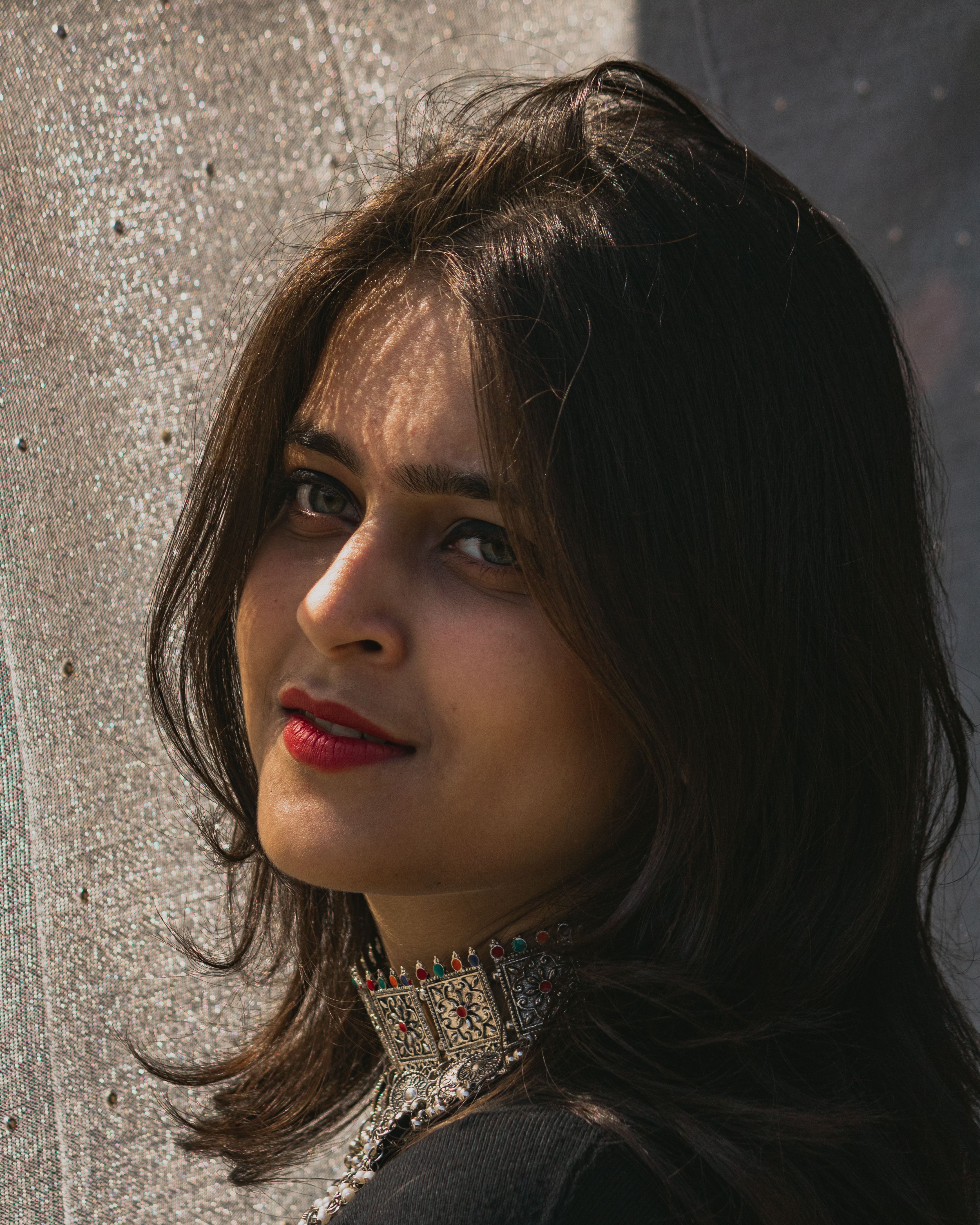 Elegant portrait of a woman posing with stylish jewelry in sunlight.
