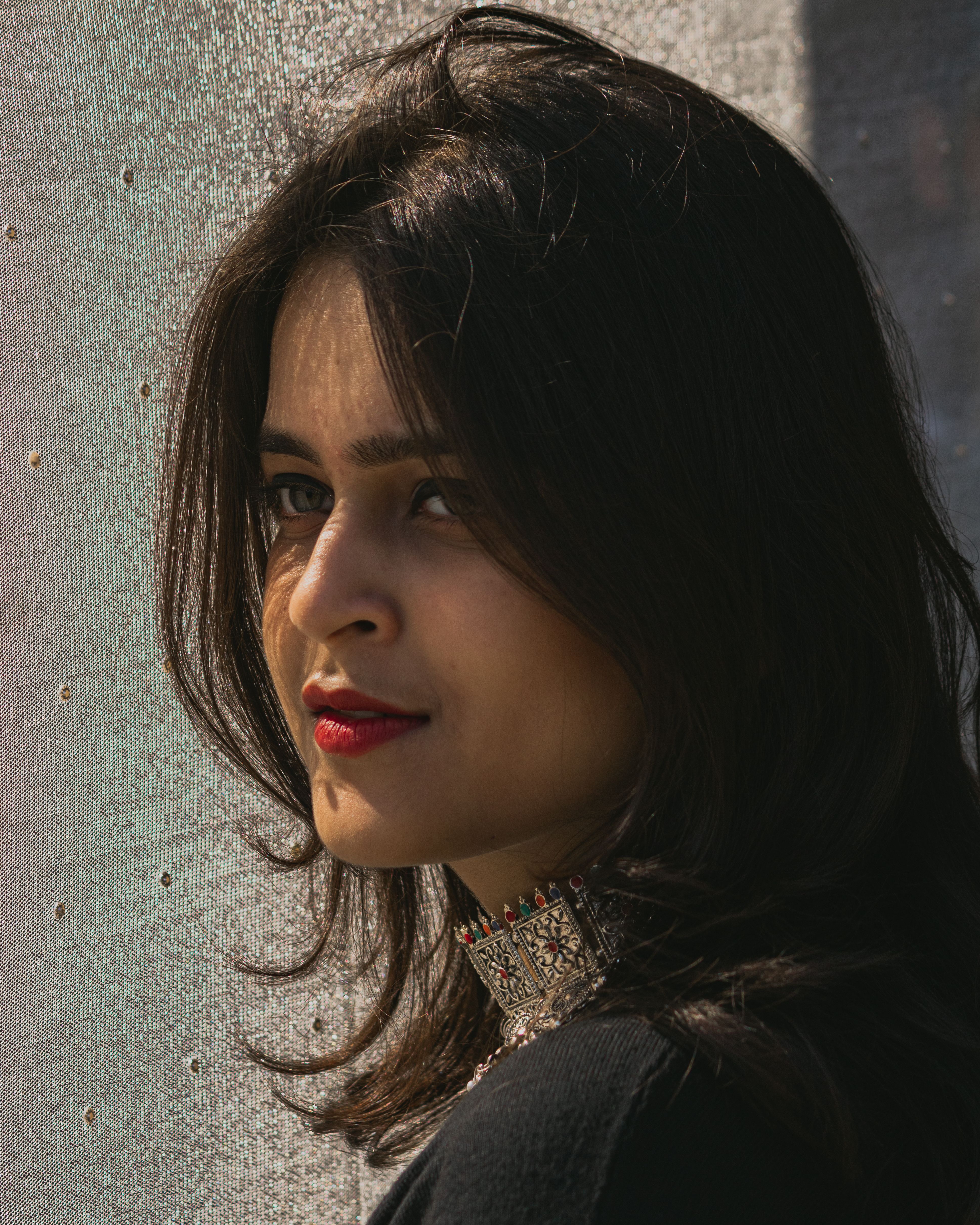 Portrait of a young woman with jewelry, illuminated by sunlight, creating a natural and warm ambiance.