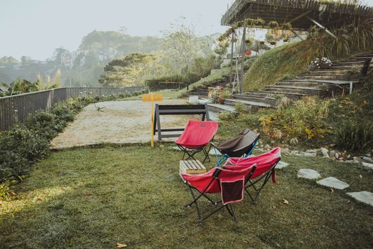 A serene garden setting with colorful chairs and scenic misty hills, perfect for a peaceful retreat.