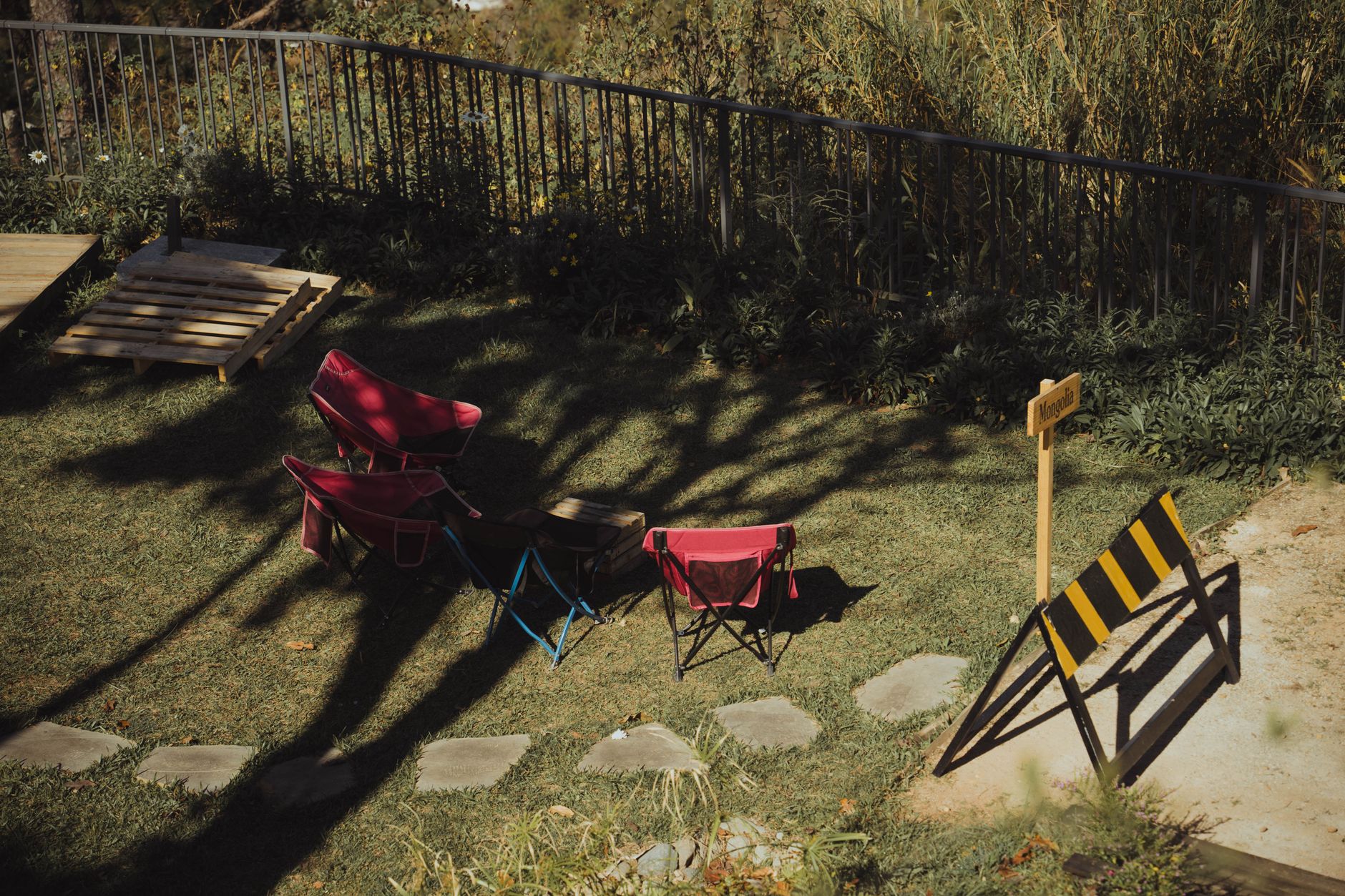 Two red chairs in a tranquil garden under sunny skies, perfect for relaxation.