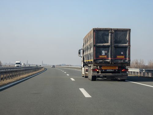 Free A cargo truck travels down an empty highway on a clear day, showcasing transportation and logistics. Stock Photo