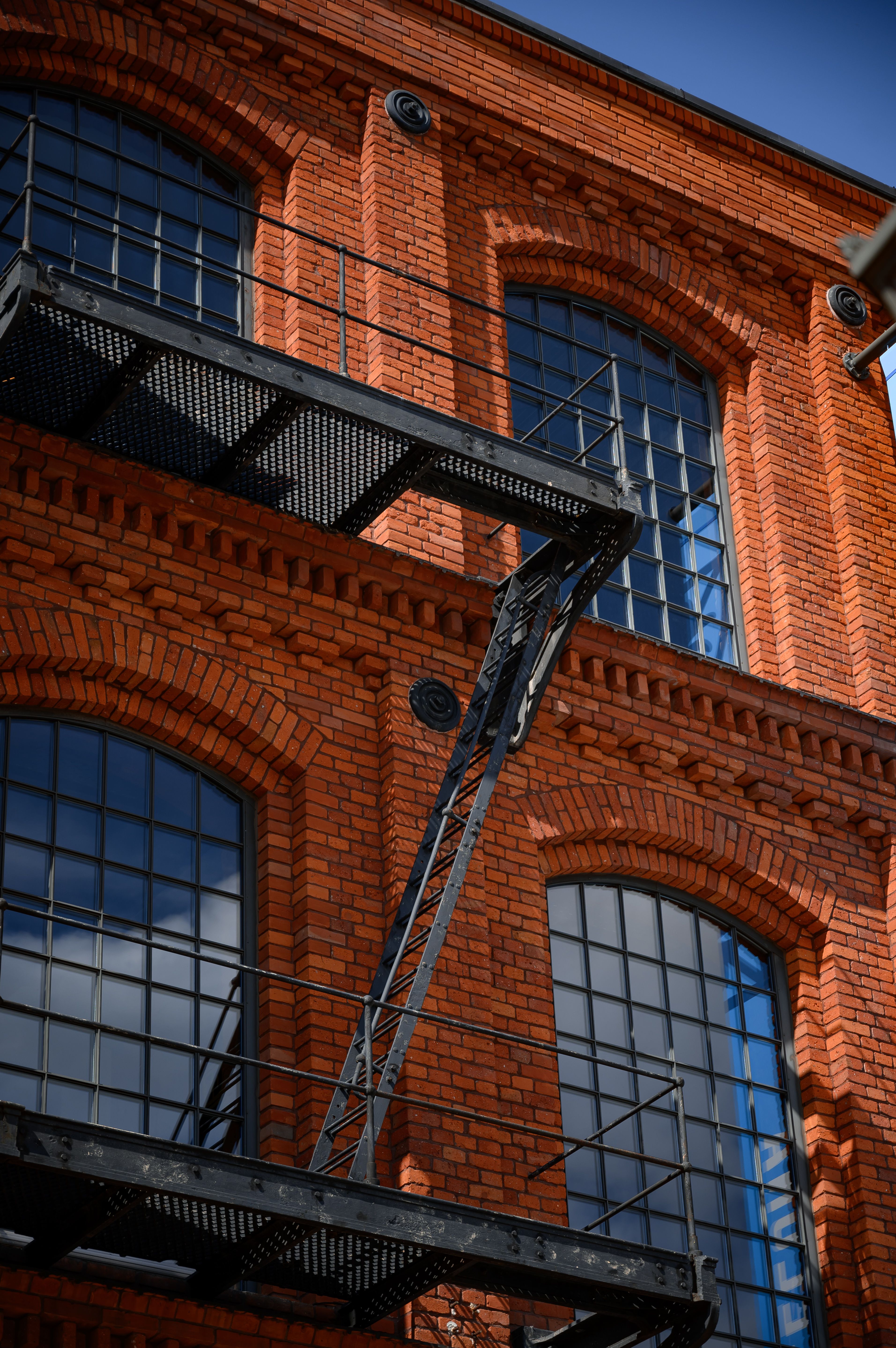 Grandes verrières à trame métallique dans la façade en brique d'une ancienne usine