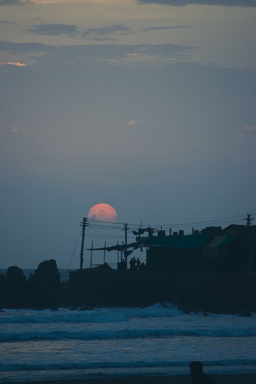 Free Serene sunset with silhouettes by the sea, capturing waves and a tranquil horizon. Stock Photo