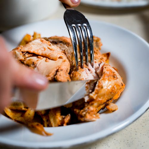 Person Cutting Chicken on a Plate 