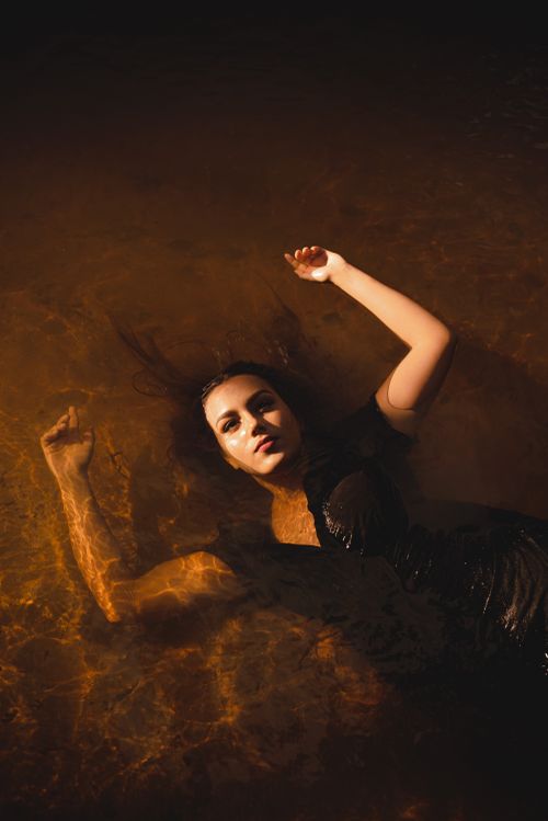 Free Captivating image of a woman in a black dress floating gracefully in water, embodying serenity and fashion. Stock Photo