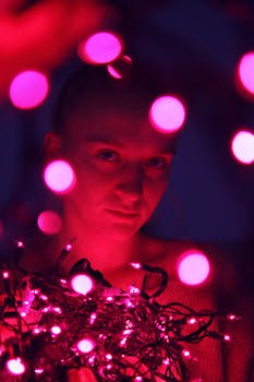 A creative portrait of a person surrounded by vibrant pink string lights with bokeh effect.