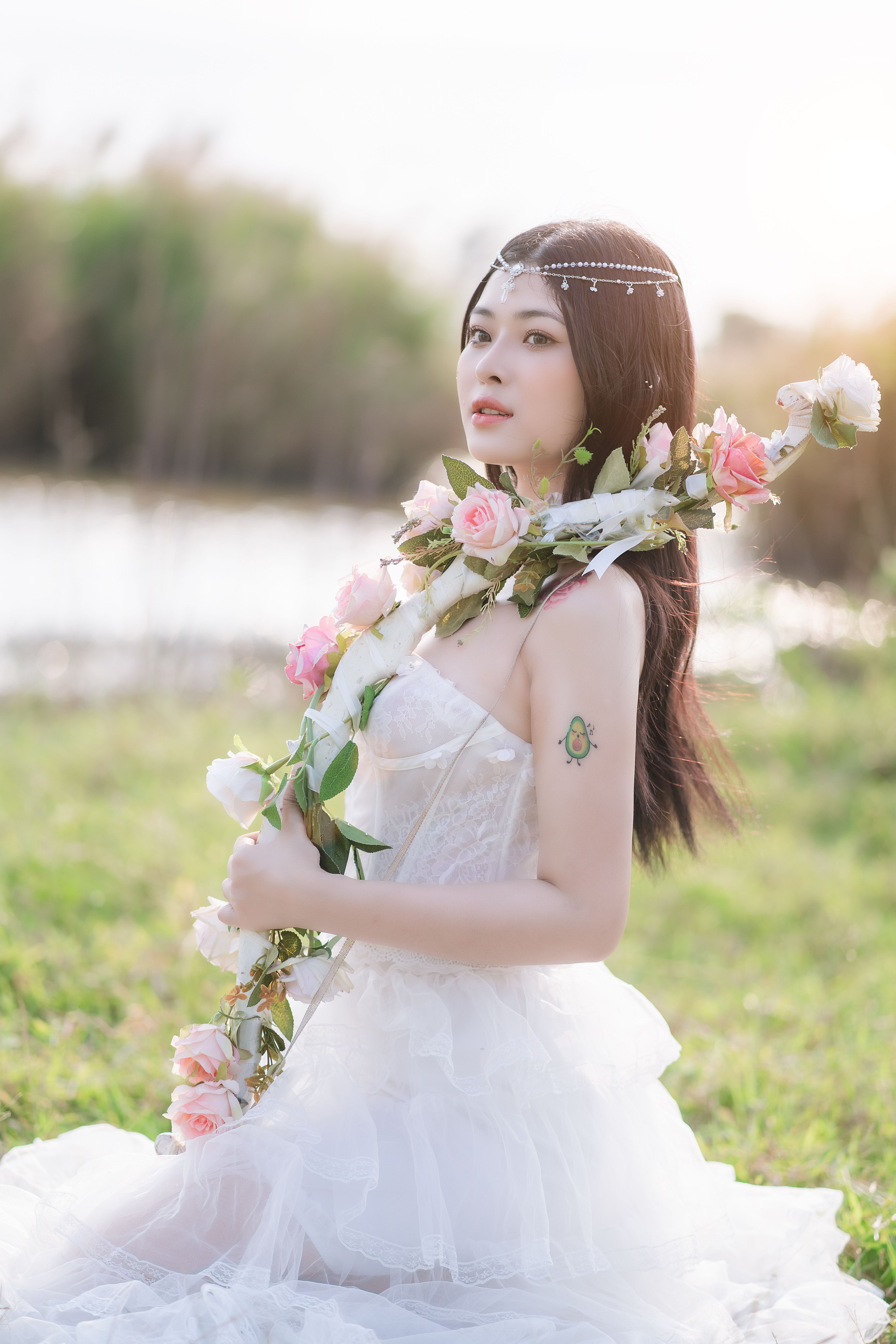 Elegant bride posing outdoors with floral decorations and a wedding dress, showcasing beauty and grace.