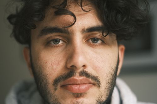 Free A close-up portrait capturing the thoughtful expression of a young man with curly hair and a beard. Stock Photo