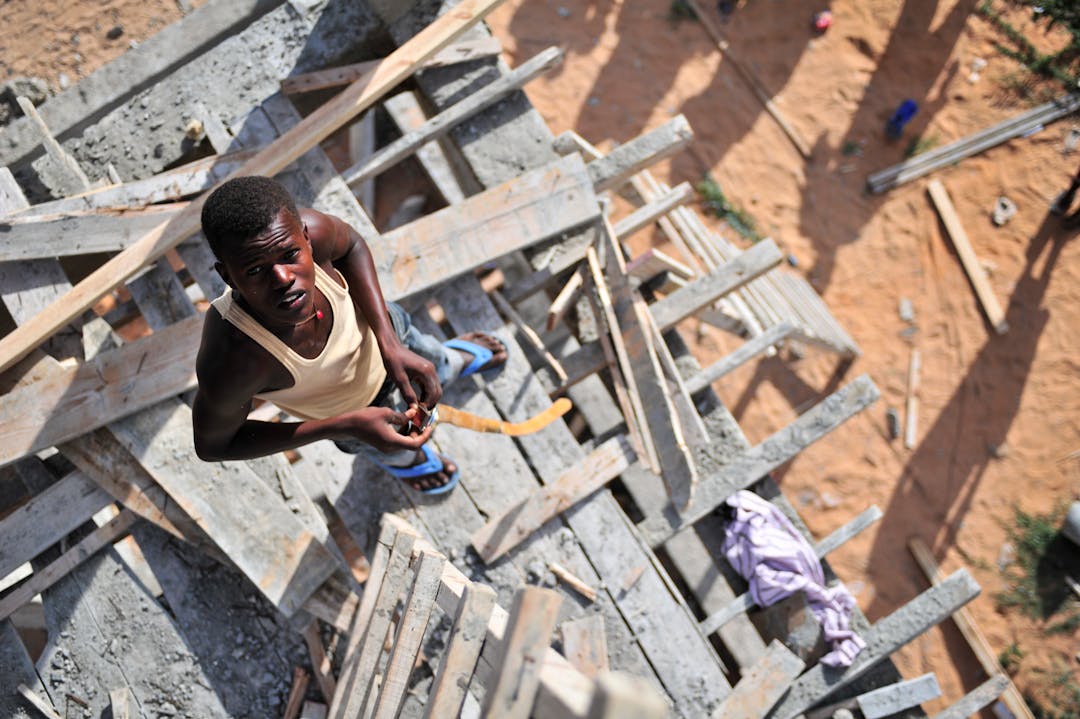 Construction worker at a building site shaping wood for structure. Top view angle.