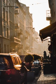 A serene morning captures the urban charm of Lviv, featuring cars and classic architecture.