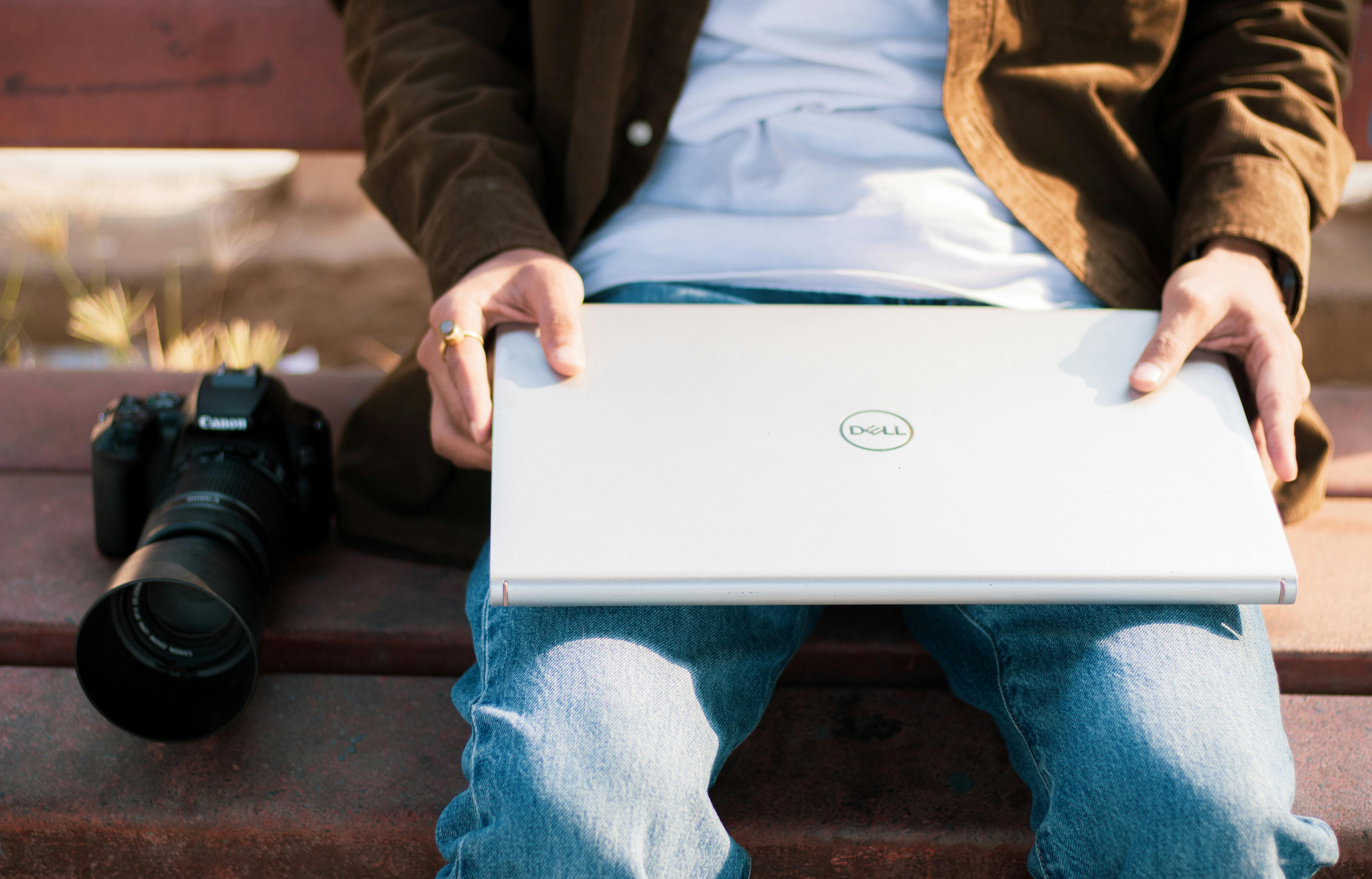 indian man is holding his laptop in his lap