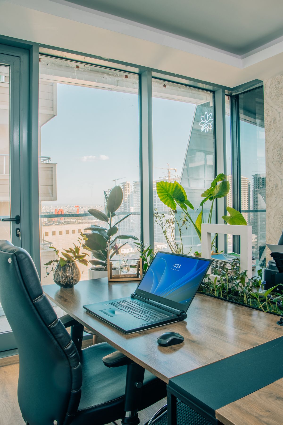 Home office pequeno em apartamento com laptop, plantas e luz natural