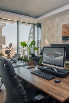 Stylish office with computer setup and cityscape view through large windows.