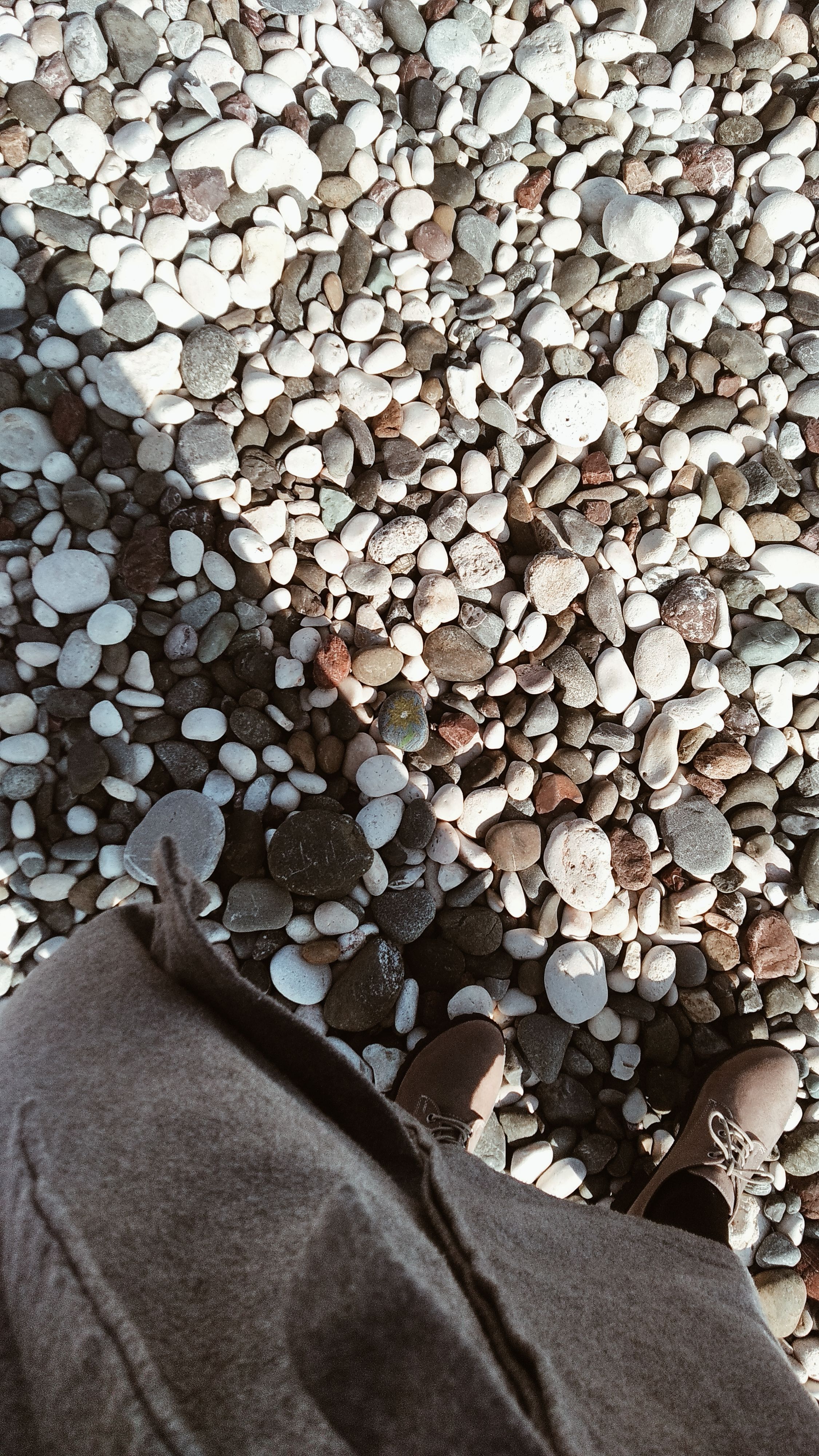 Aerial view of shoes on a pebble beach in Erdemli, Türkiye, showcasing natural textures.