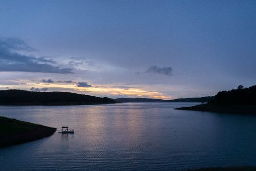 Scenic river view with sunset reflections and silhouette of forested hills.