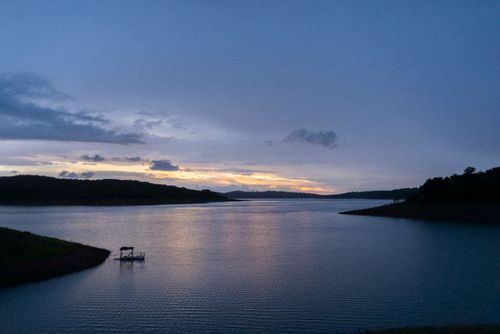 Free Scenic river view with sunset reflections and silhouette of forested hills. Stock Photo
