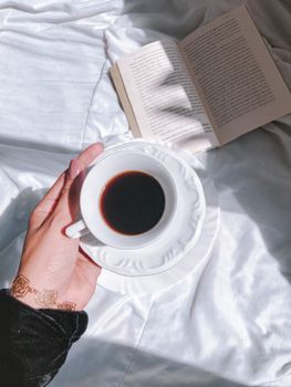 A serene morning scene with a cup of coffee held over an open book, embracing leisure.